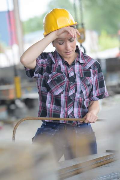 Una empleada enferma con sombrero amarillo se limpia el sudor y trata de concentrarse