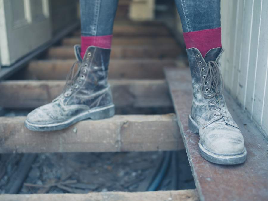 Primer plano de zapatos de seguridad polvorientos con un soporte seguro en el sitio de construcción